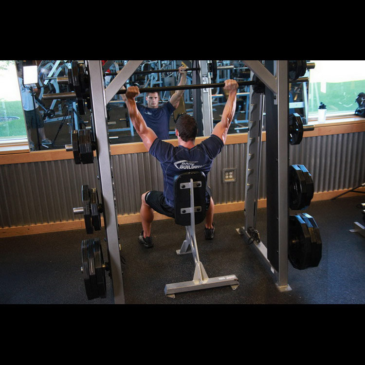 техника выполнения упражнения: Жим штанги сидя в машине Смита (Smith Machine Overhead Shoulder Press) на фото